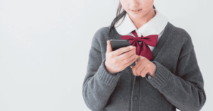 Dziewczynka w szkolnym mundurku bawiąca się smartfonem