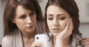 Eine Mutter und ihre Tochter schauen auf ein Smartphone.