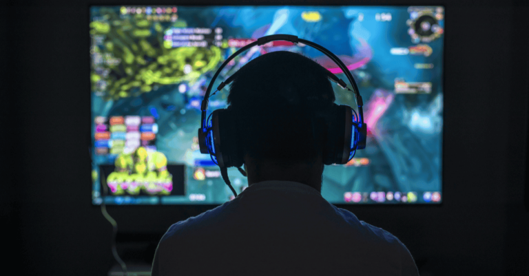 Boy with headphones on playing a game on a large screen