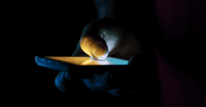 A teenager hand holding a smartphone in the dark