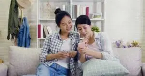 Uma mãe e uma filha usando seus telefones juntas