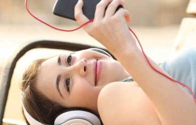 Una niña usa su teléfono inteligente afuera mientras usa auriculares.