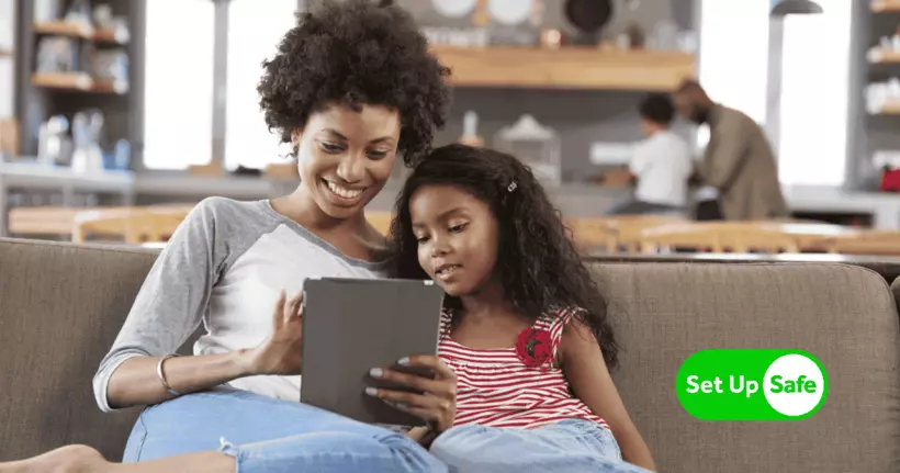 Мать и ребенок вместе смотрят на планшет. Логотип SetUpSafe из родительского контроля Internet Matters находится внизу справа.