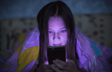 A girl looks at her smartphone at night in bed.