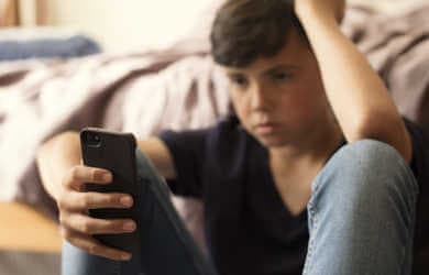 A boy looks at his smartphone, upset.