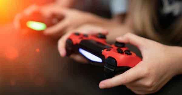 Close up of hands holding video games controllers.