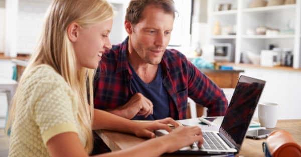 Un padre e un figlio usano insieme la tecnologia del laptop.