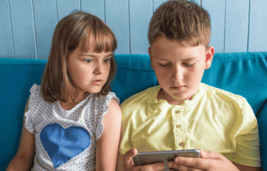 Zwei Kinder schauen auf ein Gerät.
