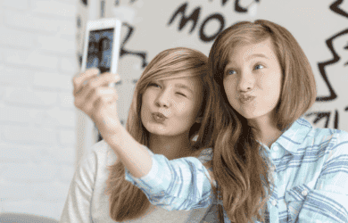 Two young girls taking a selfie on a phone