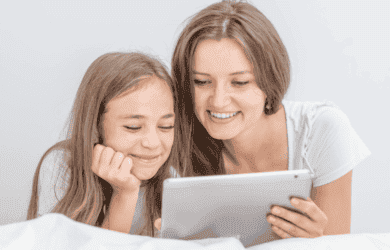 母亲和儿童微笑与她手中的平板电脑