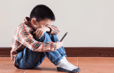 Niño sentado en el suelo mirando su teléfono inteligente