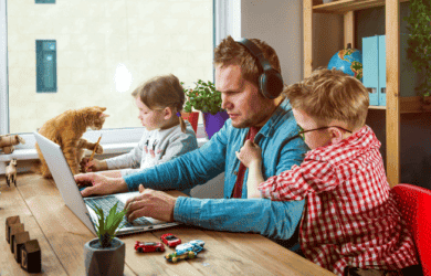 Papá con headpones sobre escribir en su computadora portátil con sus dos hijos