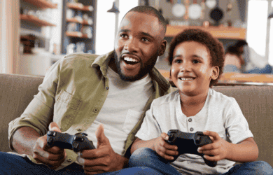 Papa und Sohn sitzen auf der Couch und spielen Videospiele
