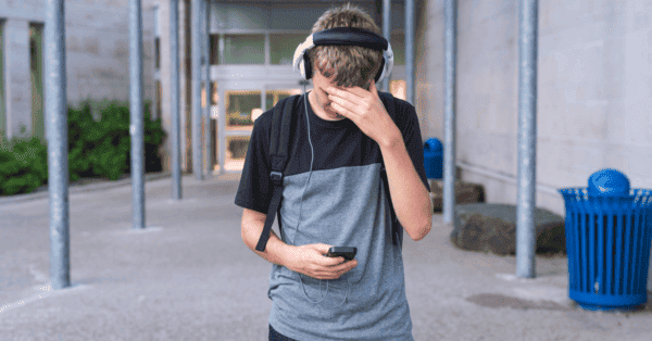 Nastoletni chłopiec z niepokojem korzysta z telefonu komórkowego
