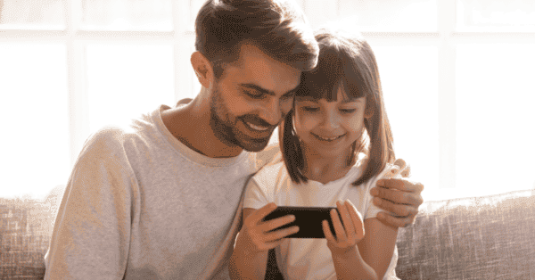 Pai e filha sorrindo para a tela do laptop
