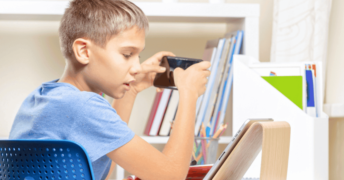 Un niño en pantalla dual con un videojuego en su teléfono inteligente y algo en su tableta.