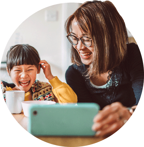 Niño y madre riéndose mirando la pantalla de un teléfono inteligente