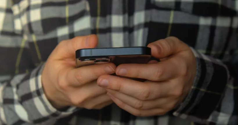 Un gros plan des mains d’une personne tenant son smartphone.