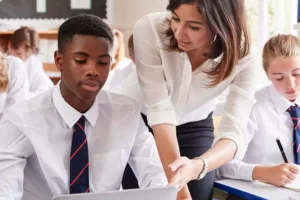 Um professor ajuda um aluno com seu laptop.