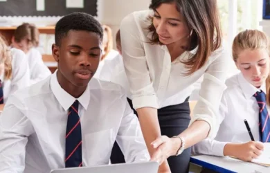 Um professor ajuda um aluno com seu laptop.