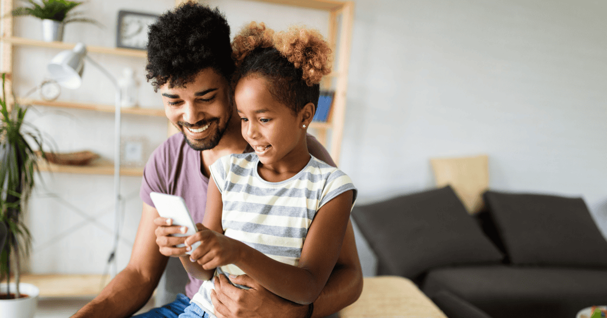 A father using a phone with his daughter