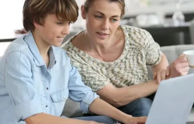Uma mãe e um filho olham juntos para um laptop.