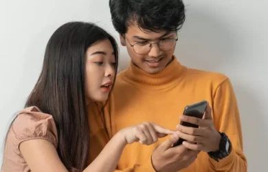 Dois adolescentes olham para um smartphone.