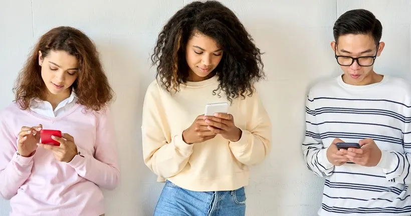 Três adolescentes usam seus dispositivos.