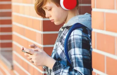 Uma criança usa fones de ouvido e um smartphone.