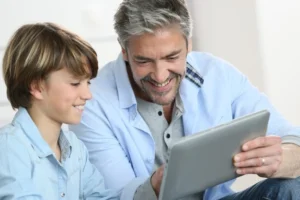 Um pai usa um tablet com seu filho.