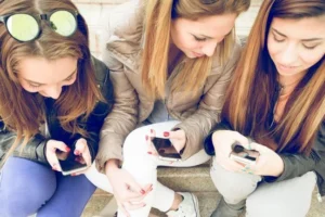 Meninas adolescentes usam seus smartphones juntas.
