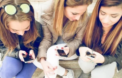 Meninas adolescentes usam seus smartphones juntas.