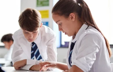 Un garçon et une fille en uniforme travaillant dans une salle de classe à l’école.