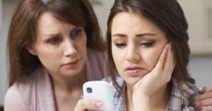 Mum and daughter with concerned facial expressions looking at a smartphone screen