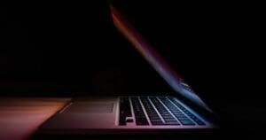 A laptop half-closed in the dark.