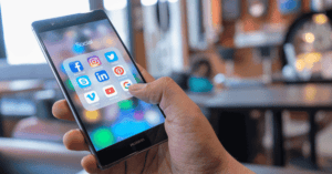 Een hand houdt een smartphone vast, waarop pictogrammen van sociale media-apps staan.
