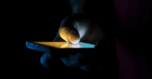 A teenager hand holding a smartphone in the dark