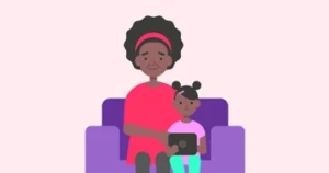 Mum and daughter siting on the sofa holding a tablet