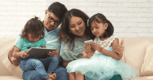 A family with young children use a smartphone and tablet together.