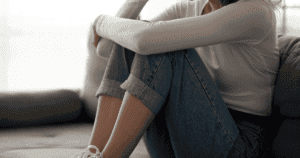 A teen sitting, holding their knees