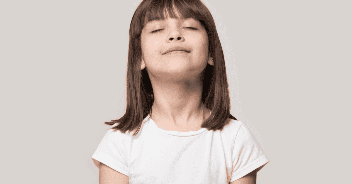 Young girl taking deep breath with eyes closed.