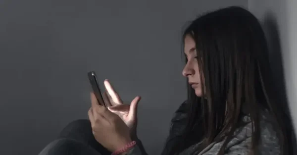 A girl on her phone, looking sad