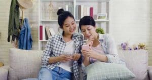 A mother and daughter using their phones together