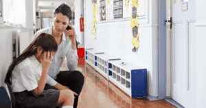 Teacher and child in corridor of school.
