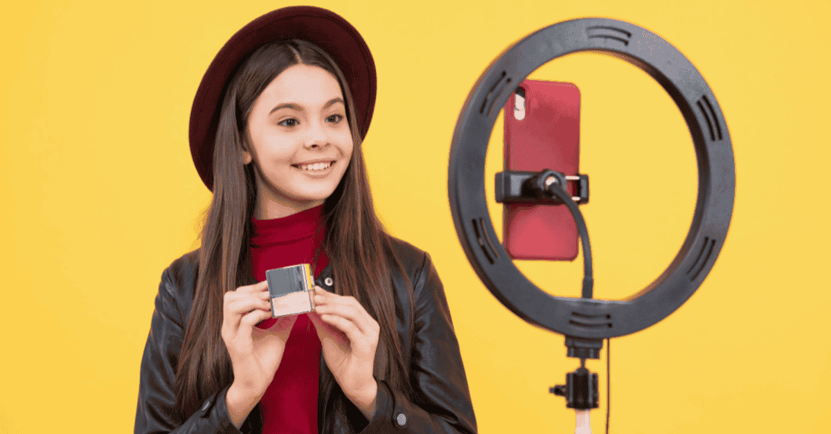 A girl holding a product in front of smartphone and ring light.