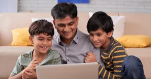 A dad and his two children look at a laptop together.