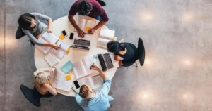 Cinq personnes sont assises autour d'une table et travaillent.