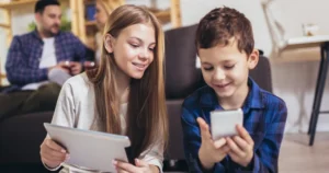 A girl and boy look at digital devices together.