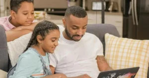 A dad and his two children use a laptop together.