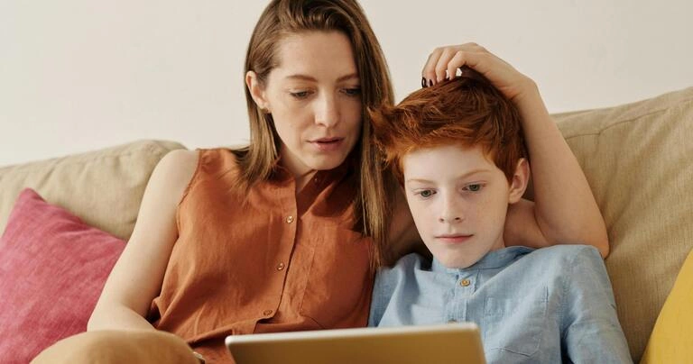 A child uses a tablet with Mum looking on.
